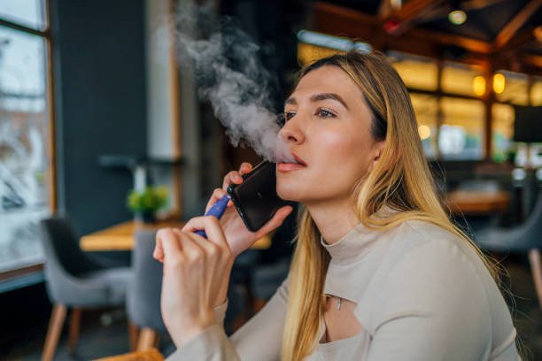 An iGet vape surrounded by caution symbols and smoke in a dark setting